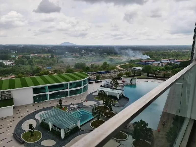 Exterior type: high-rise condominium; features: infinity pool, lap pool, pool deck with loungers, landscaped garden area, manicured lawn, outdoor dining pavilion, children's playground, surrounded by greenery, view of distant hills, modern architectural design; style: modern.