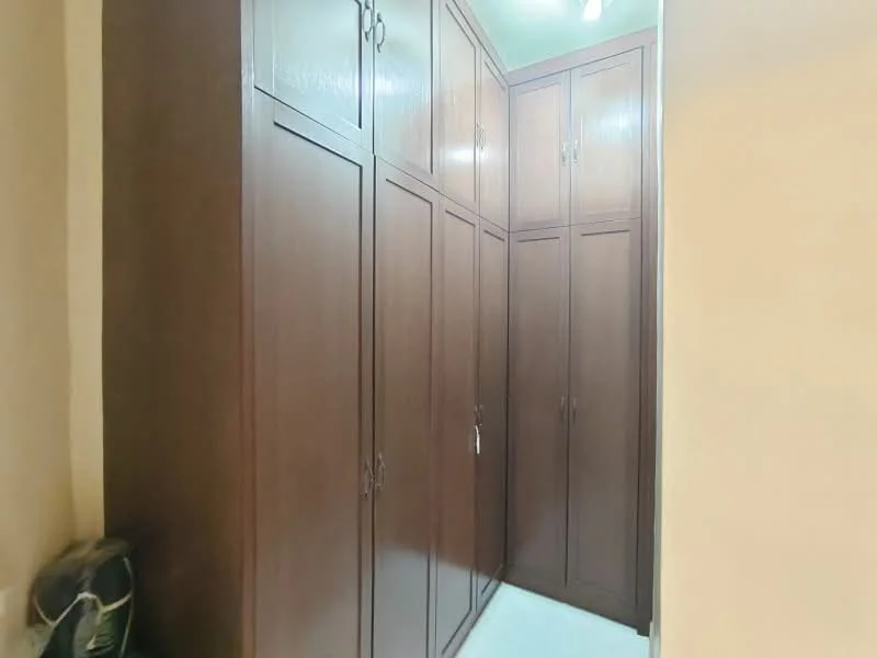Room features: built-in cabinets, wood cabinetry, multiple cabinet doors, light-colored walls, tile flooring, ceiling lights.