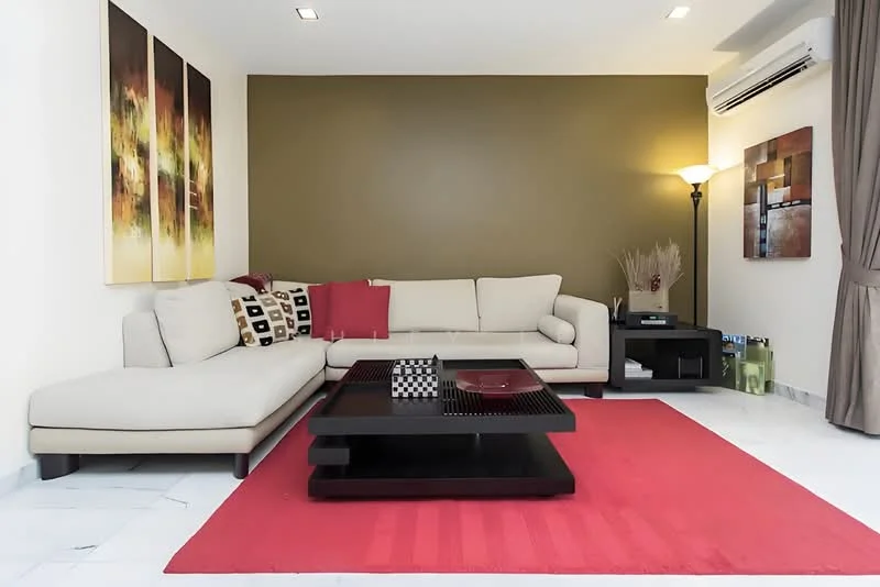 Living features: L-shape sectional sofa in cream, red accent pillows, black coffee table, area rug in red, marble flooring, green accent wall, framed artwork on walls, floor lamp, wall-mounted air conditioning unit, curtains, decorative plant in ceramic pot; style: modern.