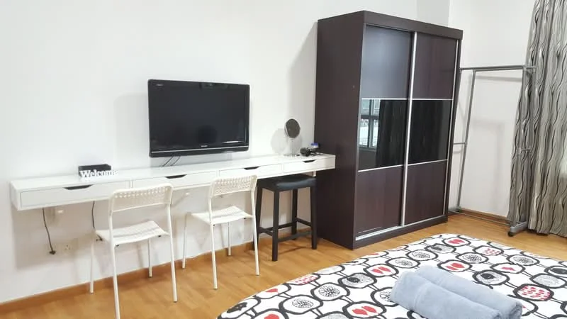 Bedroom features: queen-size bed with patterned bedding, wooden flooring, white painted walls, built-in wardrobe with sliding doors, wall-mounted flat-screen TV, white desk with two chairs, black stool, curtains with a geometric pattern, decorative welcome sign; style: modern.