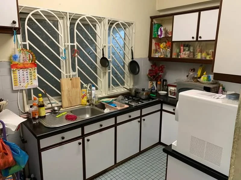 Kitchen features: black countertop, white cabinetry with wood trim, double-bowl stainless-steel sink, chrome faucet, gas stove with 4 burners, wall-mounted kitchen rack, open shelving with kitchen items, window with security bars, tile backsplash, blue and white checkered floor tiles, various kitchen appliances, wood cutting board; style: traditional.
