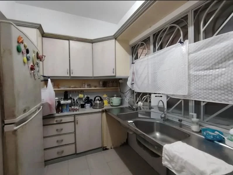 Kitchen features: white cabinetry with silver handles, stainless-steel double-bowl sink, chrome pull-down faucet, grey countertop, built-in kitchen appliances, fridge, kettle, toaster, microwave, wall-mounted shelves, tile flooring, window with protective grilles, light fixture on ceiling.
