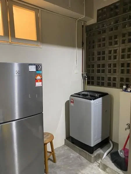 Laundry features: stainless-steel fridge, top-load washing machine, grey tiled flooring, exposed brick wall, window with frosted glass, water supply tap, drainage pipe, wooden stool.