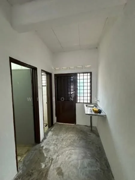 Room features: white painted walls, concrete flooring, wooden door, window with grid, metal sink on wall, light ceiling, doorway to bathroom, doorway to another room.