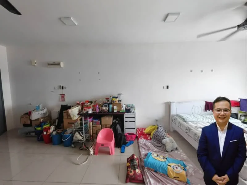 Room features: white painted walls, polished tile flooring, ceiling fan, 1 wall-mounted split AC, double bed, bedside table, pink plastic chair, storage boxes, various household items, blankets on the floor.