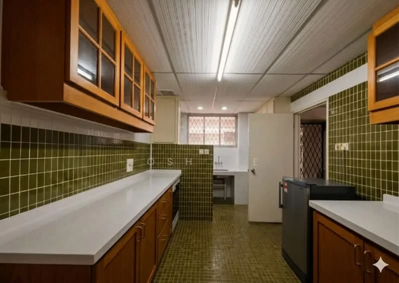 Kitchen features: brown wooden cabinetry with glass-front upper cabinets, white solid surface countertops, green tiled backsplash, green tiled walls, brown tiled flooring, built-in refrigerator, double-bowl stainless-steel sink, chrome faucet, window with security grille, overhead fluorescent lighting, open layout with access to utility area; style: traditional.