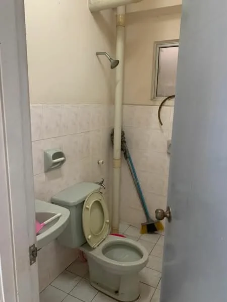 Bathroom features: white tiled walls, white ceramic floor tiles, one-piece toilet, wall-mounted sink, shower head, window, toilet paper holder, cleaning tools visible.