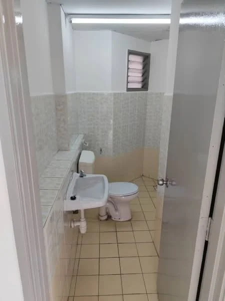 Bathroom features: white tiled walls, cream tiled flooring, single-sink vanity, toilet, shower area with glass door, wall-mounted mirror, flush-mounted ceiling light, window for ventilation.