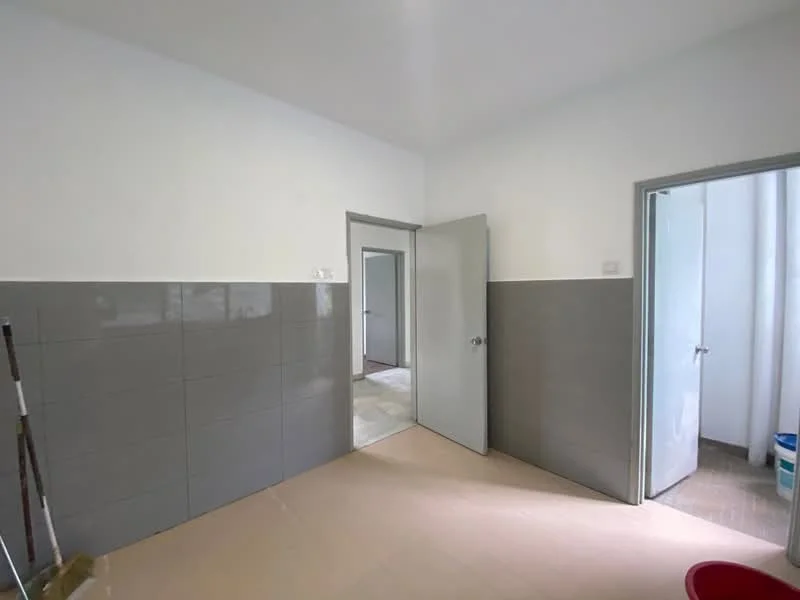 Room features: white painted walls, grey tiled wall, light-colored flooring, two doors, one door leading to another room, one door leading to a bathroom, no visible windows, minimal decor.
