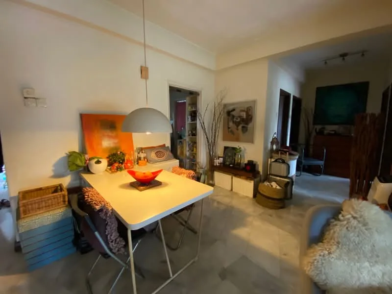 Dining features: white dining table, 4 dining chairs, pendant light fixture, decorative bowl on table, marble flooring, wall art, potted plants, woven basket, open doorway to adjacent room, decorative items on shelves; style: modern. Room features: wooden console table, decorative items, open space leading to another room.