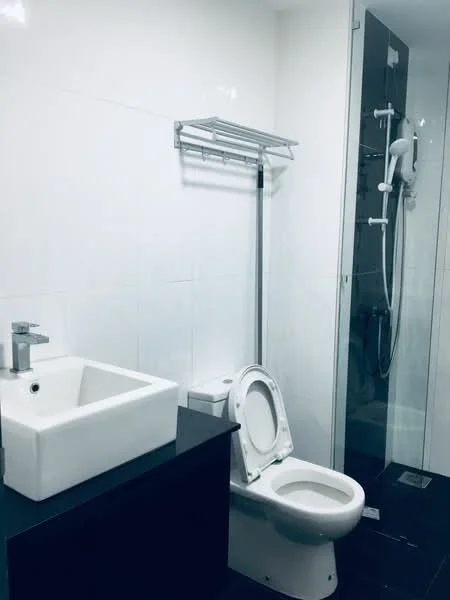 Bathroom features: white ceramic toilet, single-sink vanity with square basin, chrome basin mixer faucet, glass shower enclosure, handheld shower, wall-mounted towel rack, black cabinetry, white tiled walls, black tiled flooring; style: modern.