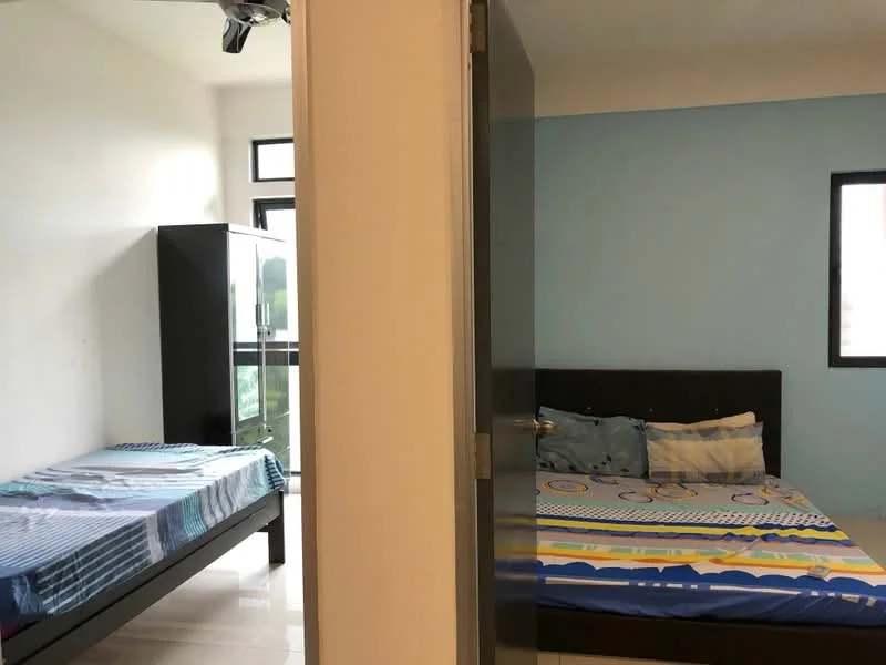 Room features: two beds, black wooden bed frame, bedding with blue and yellow patterns, light blue painted walls, white walls, floor-to-ceiling windows, sliding door, tile flooring, black wardrobe, curtains, decorative pillows; style: modern.