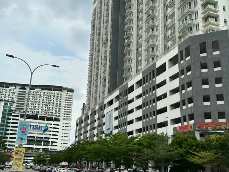 Exterior type: high-rise condominium; features: glass curtain wall, exposed concrete facade, recessed balconies, multiple storeys, commercial spaces at ground level, surrounded by greenery, parking deck, urban context with nearby buildings; style: modern.
