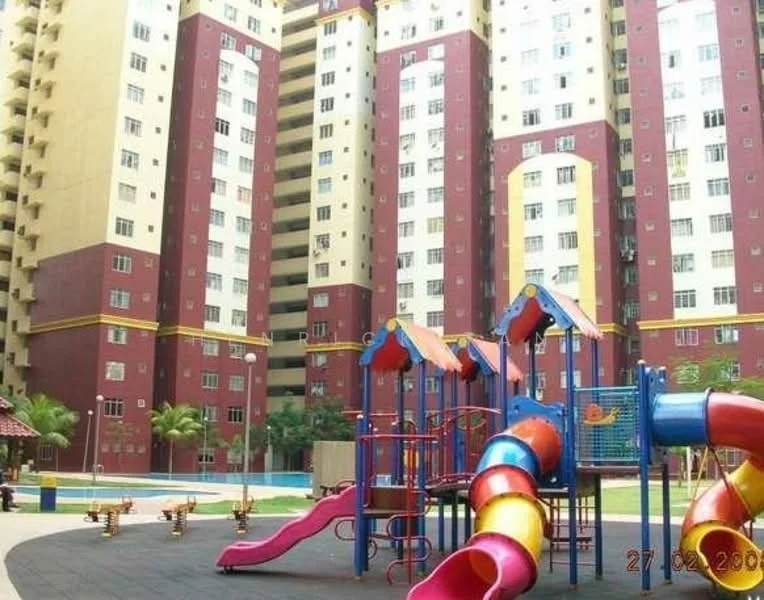 Exterior type: high-rise condominium; features: playground equipment with slides and climbing structures, swimming pool visible in the background, manicured lawn, palm trees, multi-storey residential building, red and yellow facade, balconies on upper floors; style: modern.