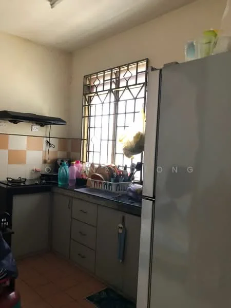 Kitchen features: grey cabinetry, black countertop, stainless-steel fridge, 4-burner gas hob, exhaust hood, double-basin sink, window with metal grille, tile backsplash with beige and brown squares, ceramic tile flooring, open shelving, various kitchen utensils and bottles on countertop.