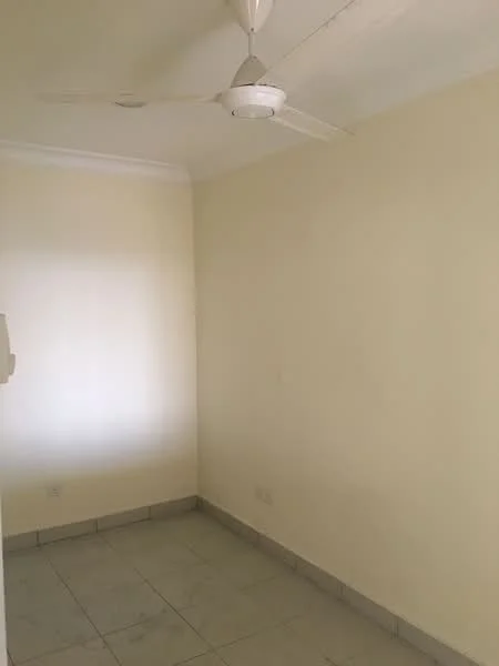 Room features: cream painted walls, ceiling fan, tile flooring, single light fixture, no visible furniture, window with natural light, corner space, minimal decor; style: minimalist.