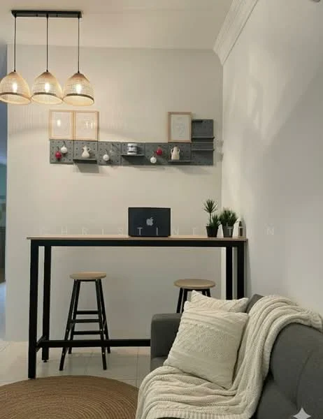 Room features: grey fabric sofa, white knitted throw blanket, round jute area rug, black bar table, 2 wooden bar stools, 3 pendant lights, wall-mounted shelf with decorative items, green potted plants, laptop on table, white painted walls, crown moulding; style: modern.