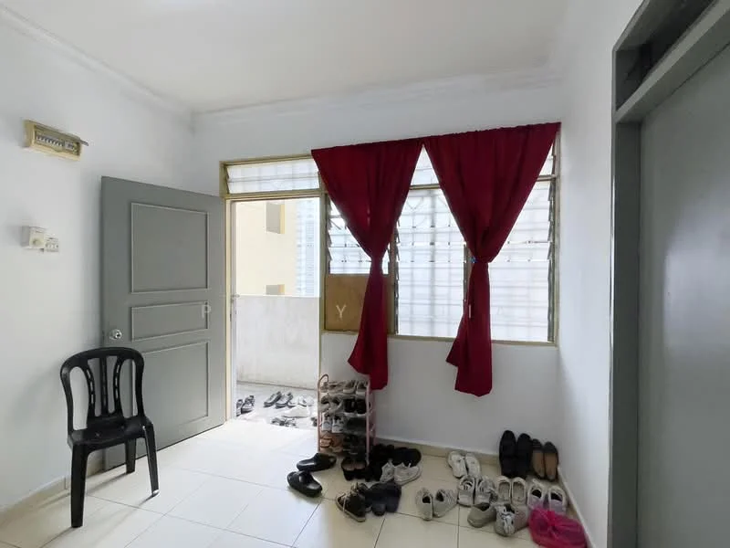 Room features: white painted walls, tile flooring, large window with sheer curtains, red curtains, black plastic chair, shoe rack, various pairs of shoes on the floor, door with grey paint.