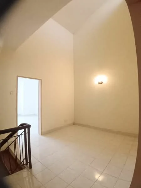 Room features: white painted walls, high ceiling, tile flooring, wall-mounted light fixture, open space, staircase railing, doorway leading to another room.