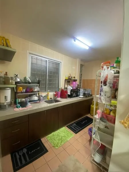 Kitchen features: laminate countertop, brown wooden cabinetry, stainless-steel sink, chrome faucet, tile backsplash, refrigerator, microwave, open shelving, floor tiles, window with grid pattern, various kitchen utensils, colorful storage containers, green area rug, wall-mounted light fixture; style: functional.