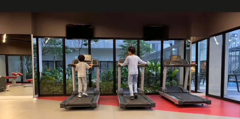 Room features: treadmill, large windows, greenery view, floor-to-ceiling windows, rubber flooring, wall-mounted TV, modern gym equipment, decorative plants, open layout, red and grey color scheme; style: modern; view: garden.