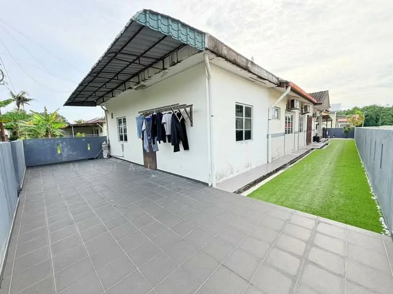 Exterior type: detached bungalow; features: flat roof, white painted facade, grey tiled roof, manicured lawn, paved walkway, clothesline with hanging clothes, surrounded by perimeter wall, outdoor space with tiles; style: modern.