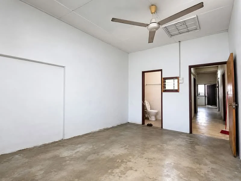 Room features: plain white walls, concrete flooring, ceiling fan, window with wooden frame, door with wooden frame, doorway leading to bathroom, doorway leading to hallway; style: minimalist.