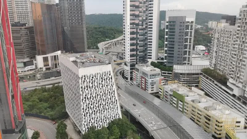 Exterior type: high-rise condominium; features: glass curtain wall, exposed concrete facade, surrounded by mature greenery, urban context with highways, multiple high-rise buildings, manicured landscaping; style: modern.