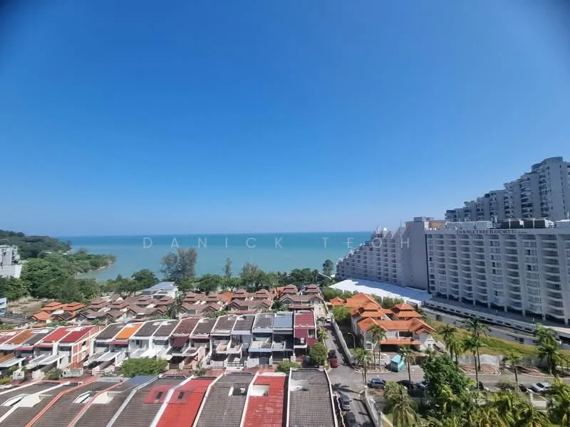 Exterior type: high-rise condominium; features: view of the sea, surrounded by residential houses, tropical landscaping, multiple storey buildings, clear blue sky, rooftops with varying colors; style: modern.