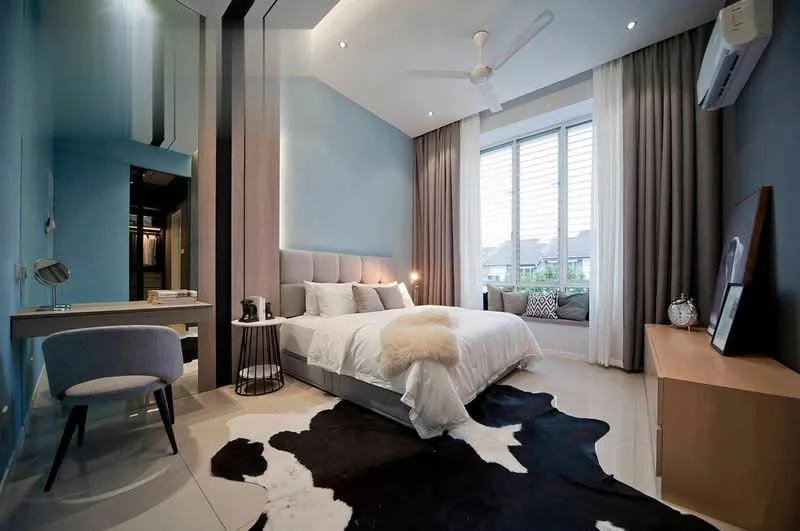 Bedroom features: king-size bed with upholstered headboard, white bedding with decorative throw, 2 bedside tables, table lamps on bedside tables, study desk with chair, floor-to-ceiling windows, sheer curtains, grey accent wall, light wood flooring, ceiling fan, wall-mounted air conditioning unit, decorative mirror, area rug with cowhide pattern; style: modern; view: garden.
