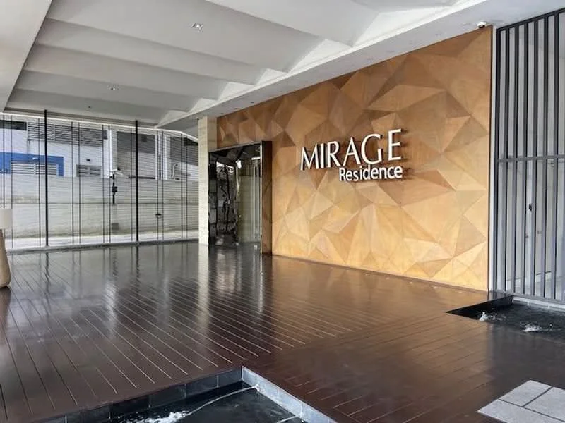 Exterior type: main entrance gate; features: wooden flooring, geometric patterned feature wall, glass facade, metal grilles, modern signage, recessed lighting, stone cladding, open space, water feature; style: modern.