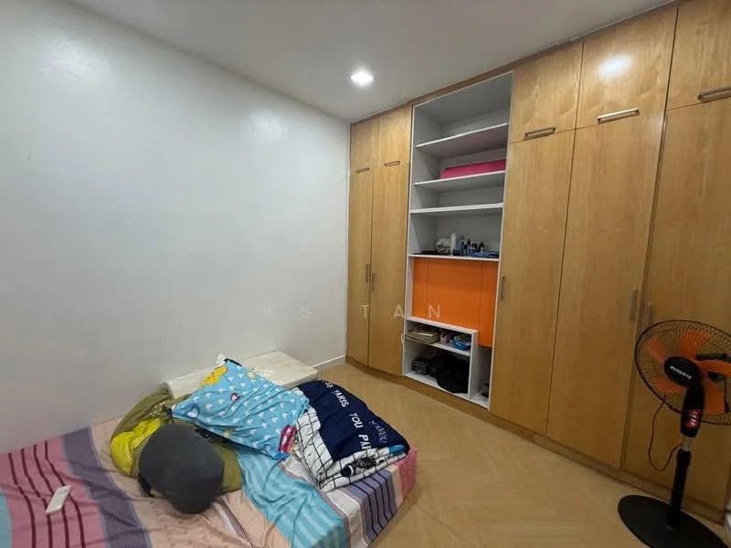 Bedroom features: white painted walls, laminate flooring, built-in wardrobe with wooden finish, orange accent shelving, bed with colorful bedding, floor fan, decorative pillows, light source on ceiling.
