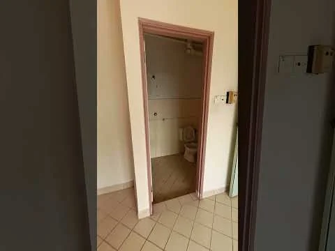 Room features: tiled flooring, light beige wall, doorway leading to bathroom, toilet visible in bathroom, neutral color scheme, light switch on wall, corner of wall visible, no visible windows.