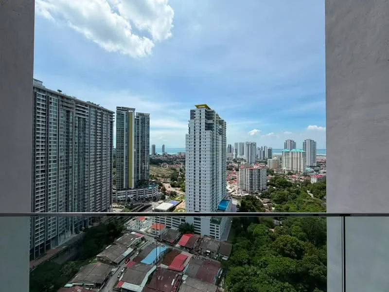 Exterior type: high-rise condominium; features: city skyline view, glass balcony railing, surrounding high-rise buildings, urban landscape, greenery in foreground, clear blue sky, partially cloudy, visible sea in background; style: modern.