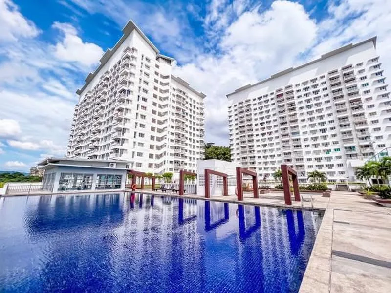 Exterior type: high-rise condominium; features: two high-rise buildings, swimming pool with blue tiles, pool deck with loungers, landscaped garden area, modern architectural design, glass curtain wall facade, balconies on residential units, manicured landscaping, outdoor seating area, surrounded by greenery; style: modern.