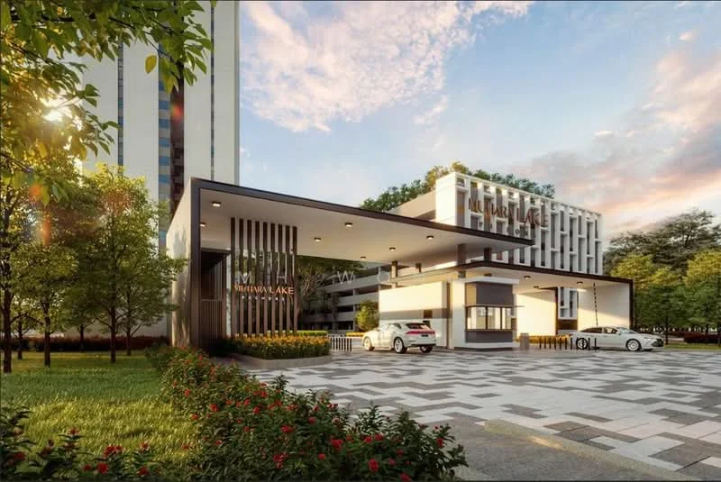 Exterior type: high-rise condominium; features: modern facade with glass and concrete, double-volume main lobby, landscaped garden with manicured lawn, paved driveway with interlocking pavers, security guard house at entrance, surrounded by mature greenery, parking area with visible cars, feature lighting at night; style: modern.