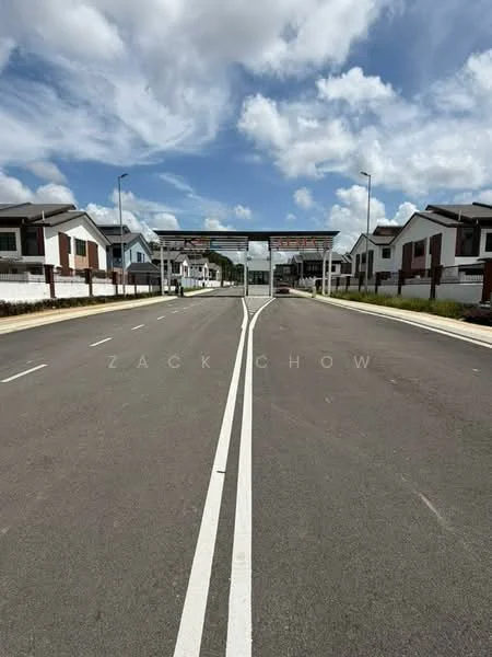 Exterior type: linked terrace house; features: newly paved road, two-lane road, street lamps, gated entrance, surrounding residential houses, manicured landscaping, white painted fences, clear blue sky, clouds, signage at entrance; style: modern.