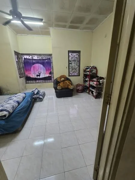 Room features: white painted walls, tile flooring, ceiling fan, large window with metal grille, purple curtain with moon and deer design, bed with blue bedding, black sofa, stuffed animals on sofa, stack of clothes on shelf, shelves with various items.