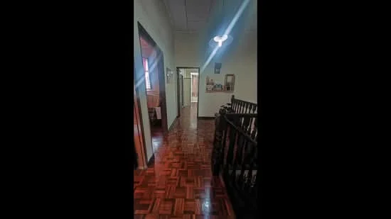 Hallway features: wooden parquet flooring, white painted walls, ceiling light fixture, wooden railing, doorways leading to other rooms, decorative wall art, framed photographs, windows allowing natural light; style: traditional.