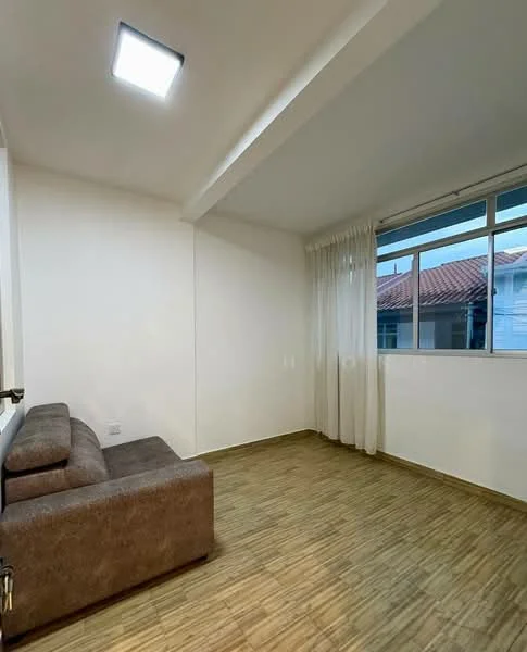 Living features: brown fabric sofa, laminate flooring, white painted walls, large window with sheer curtains, recessed ceiling light, neutral color scheme; style: modern.