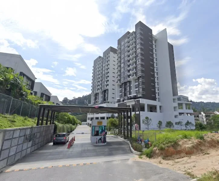 Exterior type: high-rise condominium; features: modern facade with white and dark grey cladding, multiple storeys visible, entrance gate with guard house, landscaped greenery surrounding the building, driveway leading to the entrance, parking area visible, surrounded by hilly terrain, clear blue sky in the background; style: modern.