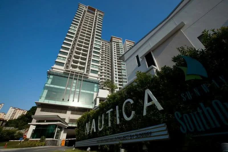 Exterior type: high-rise condominium; features: glass curtain wall, white painted facade, recessed balconies, feature lighting at night, surrounded by mature greenery, signage at entrance, modern architectural design; style: modern.