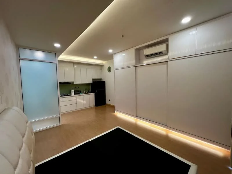 Living features: white painted walls, wood laminate flooring, recessed downlights, built-in cabinetry, wall-mounted air conditioning unit, sliding glass door, black area rug, kitchenette with white cabinets, green backsplash, microwave, stainless-steel sink, countertop, open layout; style: modern.