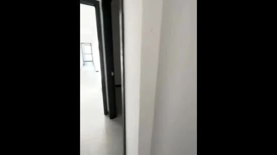 Room features: white painted walls, grey tiled flooring, black door frame, door leading to another room.