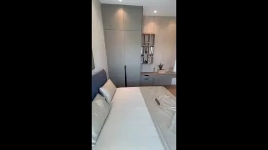 Bedroom features: queen-size bed with grey upholstered headboard, light grey bedding, built-in wardrobe with sliding doors, wooden bedside table, decorative wall shelf, recessed downlights, neutral wall colour, flooring not visible; style: modern.