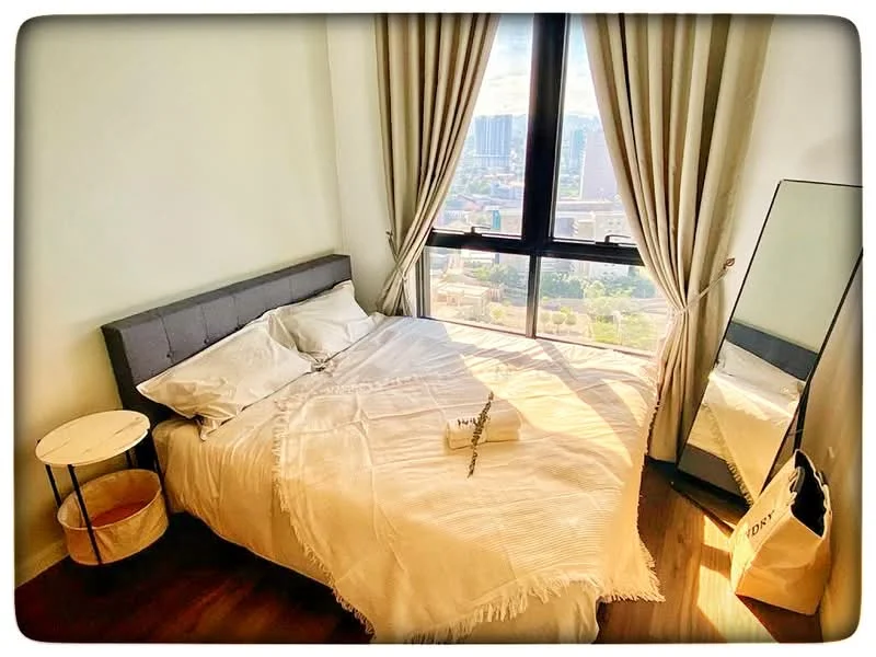 Bedroom features: king-size bed with white bedding, upholstered headboard in grey, floor-to-ceiling window, sheer curtains, wooden flooring, round side table, full-length mirror, decorative throw blanket; style: modern; view: city.