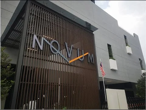 Exterior features: modern facade, grey exterior walls, large signage with the word 'NOVIUM', horizontal slatted screen, planters integrated into the facade, flagpole with Malaysian flag, multiple levels visible, glass windows, architectural detailing; style: modern.