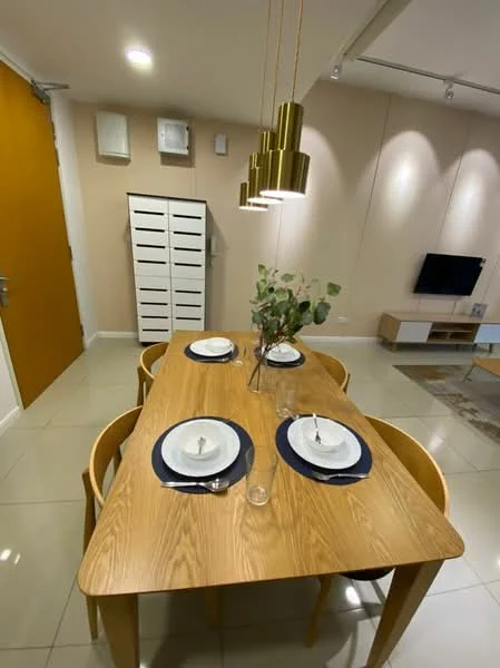 Dining features: wood dining table, 4 wooden dining chairs, white plates on the table, glass vase with greenery, gold pendant lights, neutral wall color, tile flooring, wall-mounted TV, storage cabinet, air conditioning unit; style: modern.