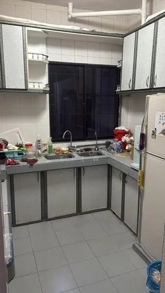 Kitchen features: grey laminate countertop, double-bowl stainless-steel sink, chrome pull-down faucet, white cabinetry with grey trim, built-in refrigerator, ceramic tile flooring, wall-mounted shelves, window with black frame, kitchen appliances visible, various utensils and containers on countertop.