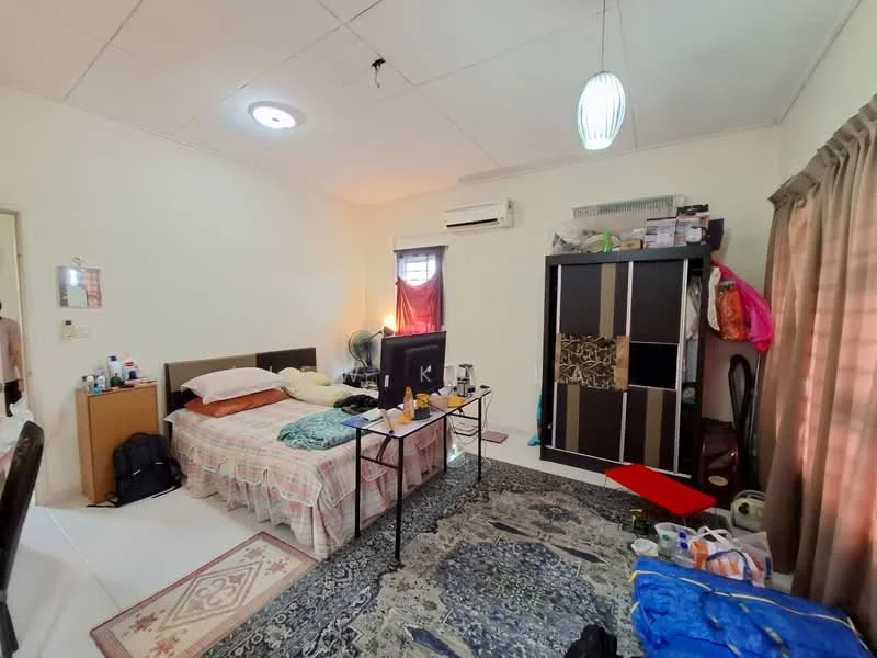 Bedroom features: queen-size bed with beige bedding, wooden headboard, 2 bedside tables, table lamp, wall-mounted air conditioning unit, ceiling light fixture, large wardrobe with sliding doors, area rug with intricate pattern, window with sheer curtains, folding table, television on a stand, cluttered storage items, wall-mounted fan.